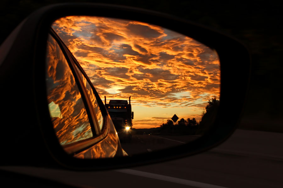 An 18-wheeler riding our bumper is illuminated by a brilliant reddish-orange sunset along Route 22 in Westmoreland County, PA. Captured in the passenger-side mirror at 65 mph.
